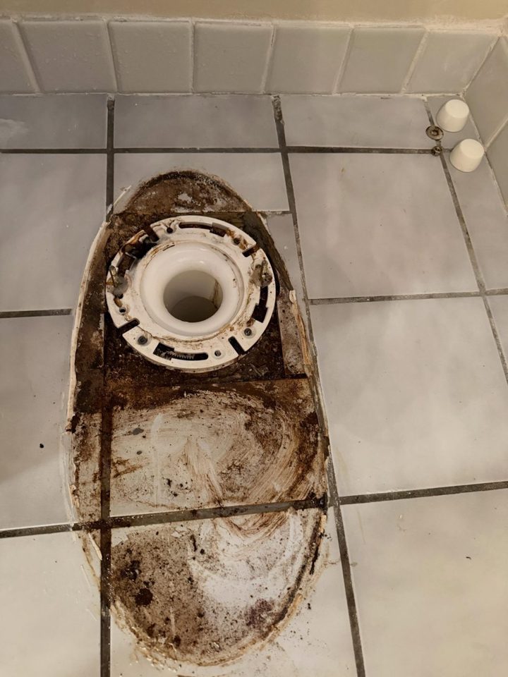 Before: the old toilet flange and stained floor after removal